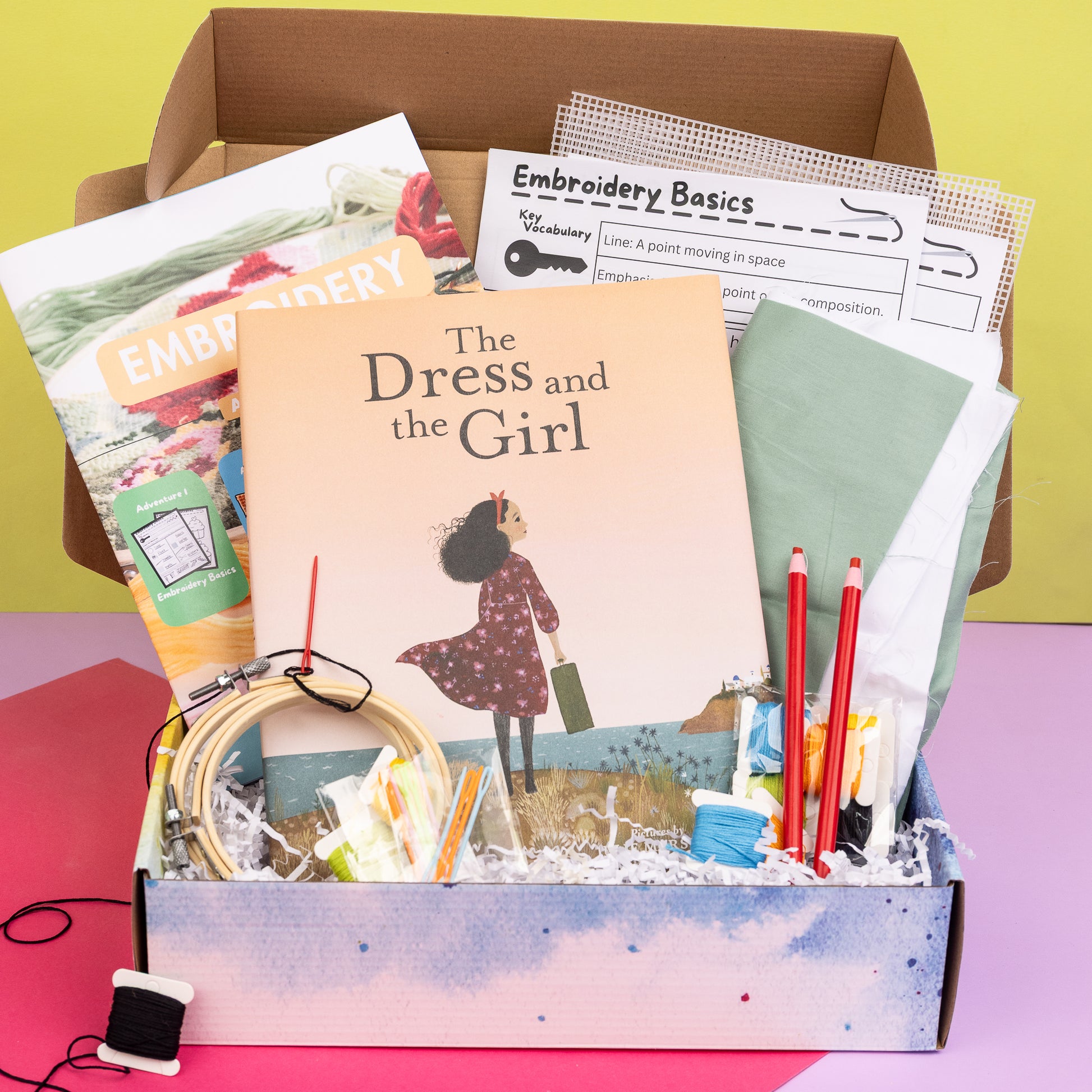 Picture of a packed Embroidery Art Box including The Dress and the Girl book, project instructions, activity sheets, fabric, burlap, embroidery needles, floss, fabric pencils, embroidery hoops, and mesh canvas.