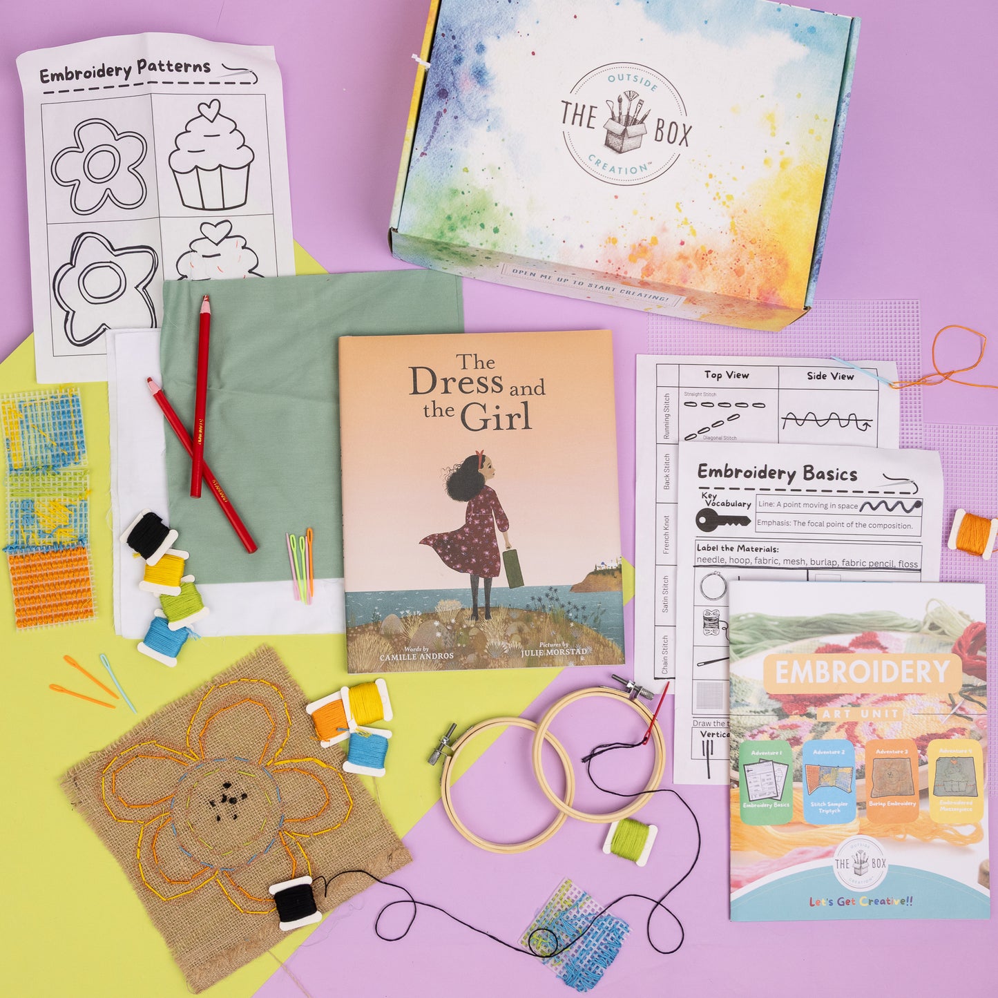 A flat lay picture of the Embroidery Art Box including The Dress and the Girl book, project instructions, activity sheets, fabric, burlap, embroidery needles, floss, fabric pencils, embroidery hoops, and mesh canvas as well as some of the finished projects including a burlap flower and stitch sampler.